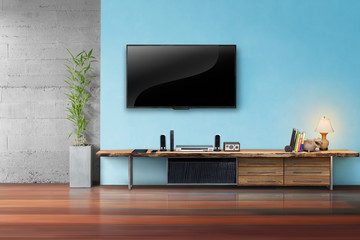 Tv on light blue wall with wooden table and plant in pot living