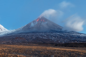 Volcanic landscape of Kamchatka: eruption Klyuchevskoy Volcano, lava flows on slope of volcano; plume of gas, steam, ash from crater. Kamchatka Peninsula, Russia, Klyuchevskaya Group of Volcanoes.