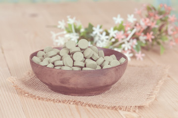 Herbal pill on wooden bowl. herb for healthy living.
