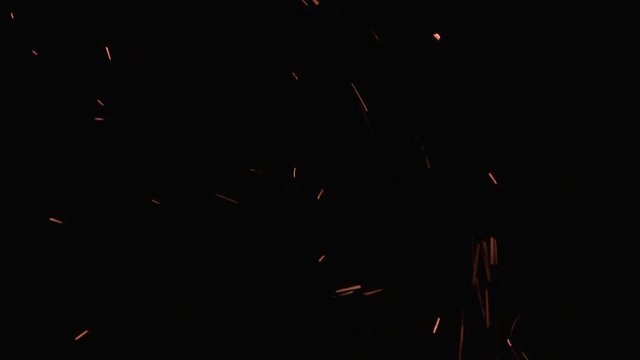 Burning ash rising from fire in the night sky, moderate amount of sparks for background.