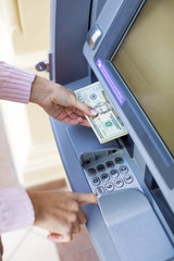 Woman hand withdrawing money from outdoor bank ATM