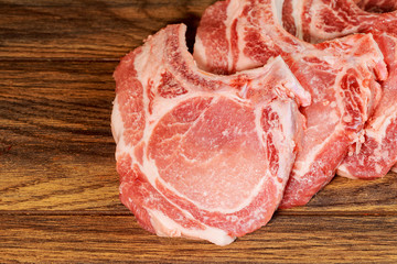 Pieces raw pork steak with wooden background in rustic style,