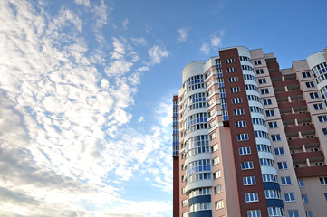 Fototapeta premium A modern multistory apartment house with round balconies against the blue sky. Lookup.