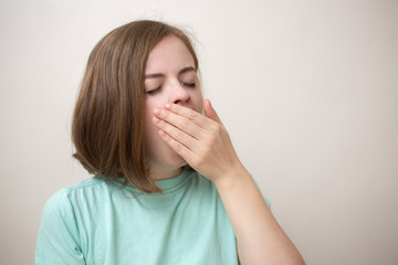 Portrait of blonde girl or young woman wearing blue green t-shirt with perplexed, puzzled, dumb, ignorant expression on her face scratching head with hand. When you don't know the answer