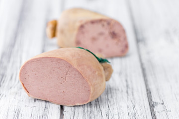 Liverwurst (German cuisine) on wooden background (selective focu