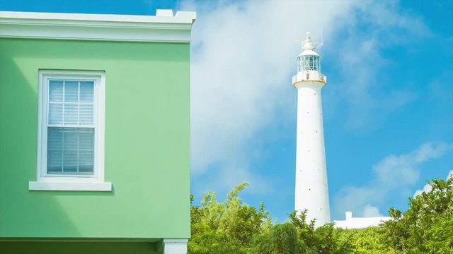 Gibb's Hill Lighthouse in Southampton, Bermuda, Standing Adjacent to a Green Bermudan Architectural Style Building on a Sunny Day with a Blue Sky Background