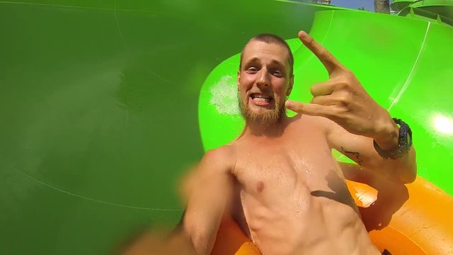 Young funny mixed race couple halfpipe slide selfie in water park. GoPro selfie HD. Bali, Indonesia