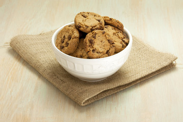 Bowl of chocolate chips cookies on burlap with copyspace
