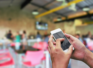 Hand touch screen smartphone with abstract blur restaurant .