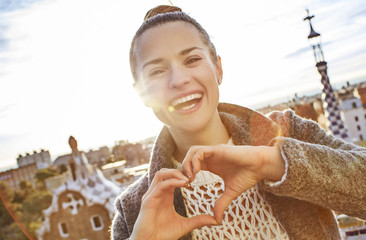 Naklejka premium smiling woman at Guell Park showing heart shaped hands