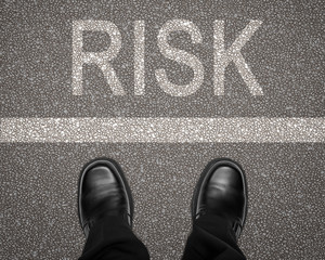 Risk concept with feet on road behind white line