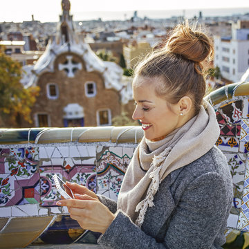 traveller woman at Guell Park in Barcelona, Spain writing sms