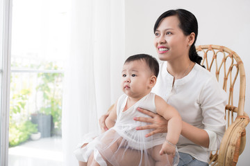 Portrait of happy asian mother and baby having fun together at home