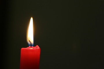 Rote Kerze mit Flamme und dunklem Hintergrund