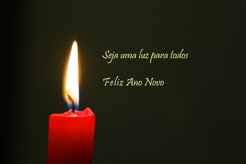 Rote Kerze mit Flamme und dunklem Hintergrund mit portugiesischem Text