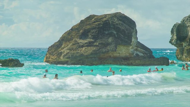 People Swimming Amongst Big Rocks at Horseshoe Bay, Bermuda with a Tropical Colored Water Surf on a Sunny Day