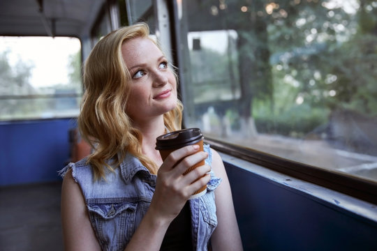 Beautiful girl with cup of coffee in trolleybus
