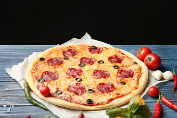 Tasty pizza on blue wooden table with black background