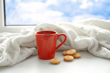Cup of fresh coffee and knitted plaid on windowsill
