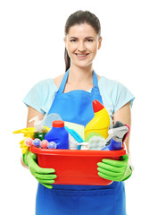 Young cleaner with cleaning supplies in basin on white background