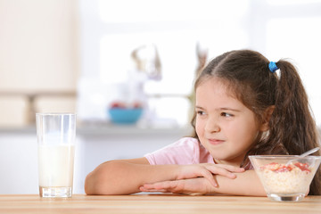 Obraz na płótnie Canvas Cute little girl refusing to drink milk