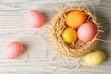 Basket with colorful Easter eggs on wooden table