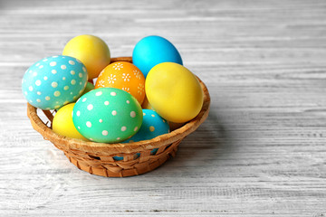 Basket with colorful Easter eggs on wooden table