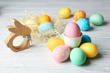 Fototapeta na wymiar Decorative nest with colorful Easter eggs and bunny figure on wooden background