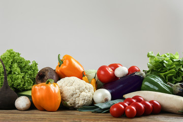 Fresh vegetables on wooden table against light background