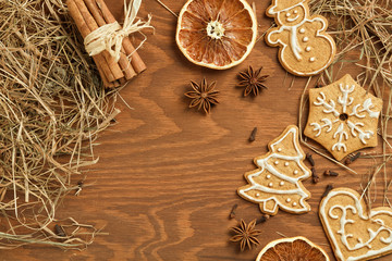 Christmas gingerbread on brown, wooden background with various decoration and spices