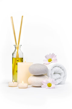 Spa decoration with stones, daisies, candles and a bottle with massage oil on a white background