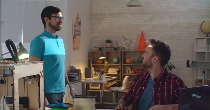 PAN of engineer in glasses standing still while his colleague scanning him for 3d printing project 