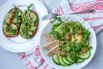Green salad with avocado, couscous and tofu. Open sandwiches with avocado and arugula.  Love for a healthy raw food concept.
