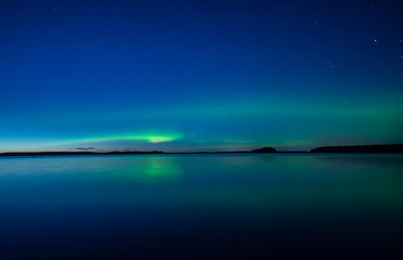 Fototapeta na wymiar Northern lights dancing over calm lake