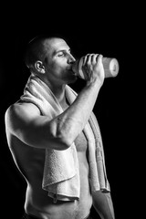 Fototapeta na wymiar Young man holding white towel and drinking water isolated on bla