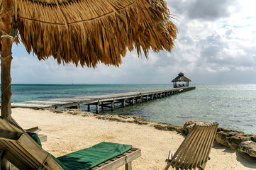Wooden wharf in Caribbean sea as seen from under beach umbrella