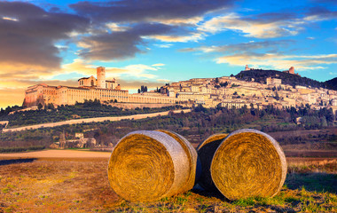 Italian countryside with hey rolls with view of impressive Assis - obrazy, fototapety, plakaty