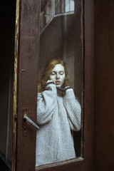 Obraz premium Sensual young model with freckles behind the old glass door