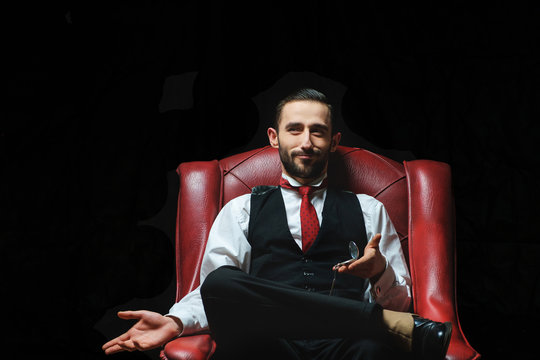side view of an elegant young businessman smoking a cigarette on black studio background