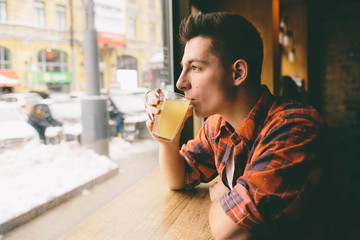 Young student is sitting in the restaurant and taste a warm drink. man drinking  tea at the cafe