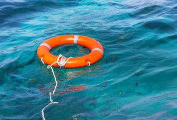 orange life buoy safety equipment floating in the sea 