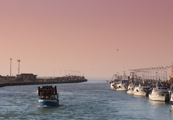 Fishing ships at sunset in the harbor of Fiumicino, Rome, Italy