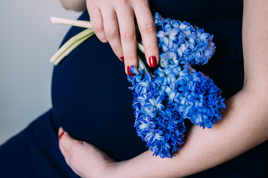 Pregnant woman in dark blue dress sitting with bouquet of flowers