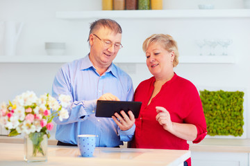 elderly couple surfing online on tablet, at home
