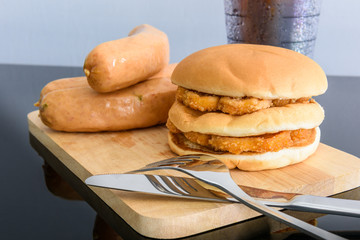 pork sausage, chicken hamburger and glass of cola on wooden cutt