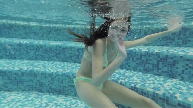 Teenager in pool under water waving