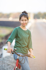 Obraz premium Young asian woman with red bicycle in a park - outdoor portrait