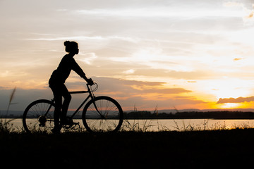Obraz premium Biker-asian girl at the sunset on the meadow
