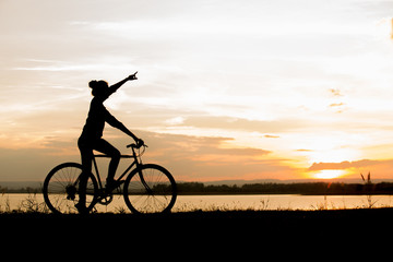 Obraz premium Biker-asian girl at the sunset on the meadow