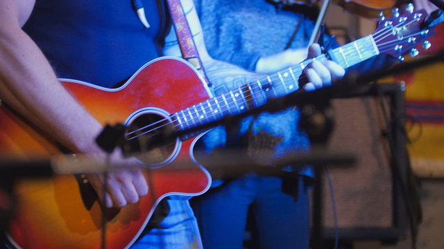 Muscular musician - guitarists - plays concert acoustic guitar in night club